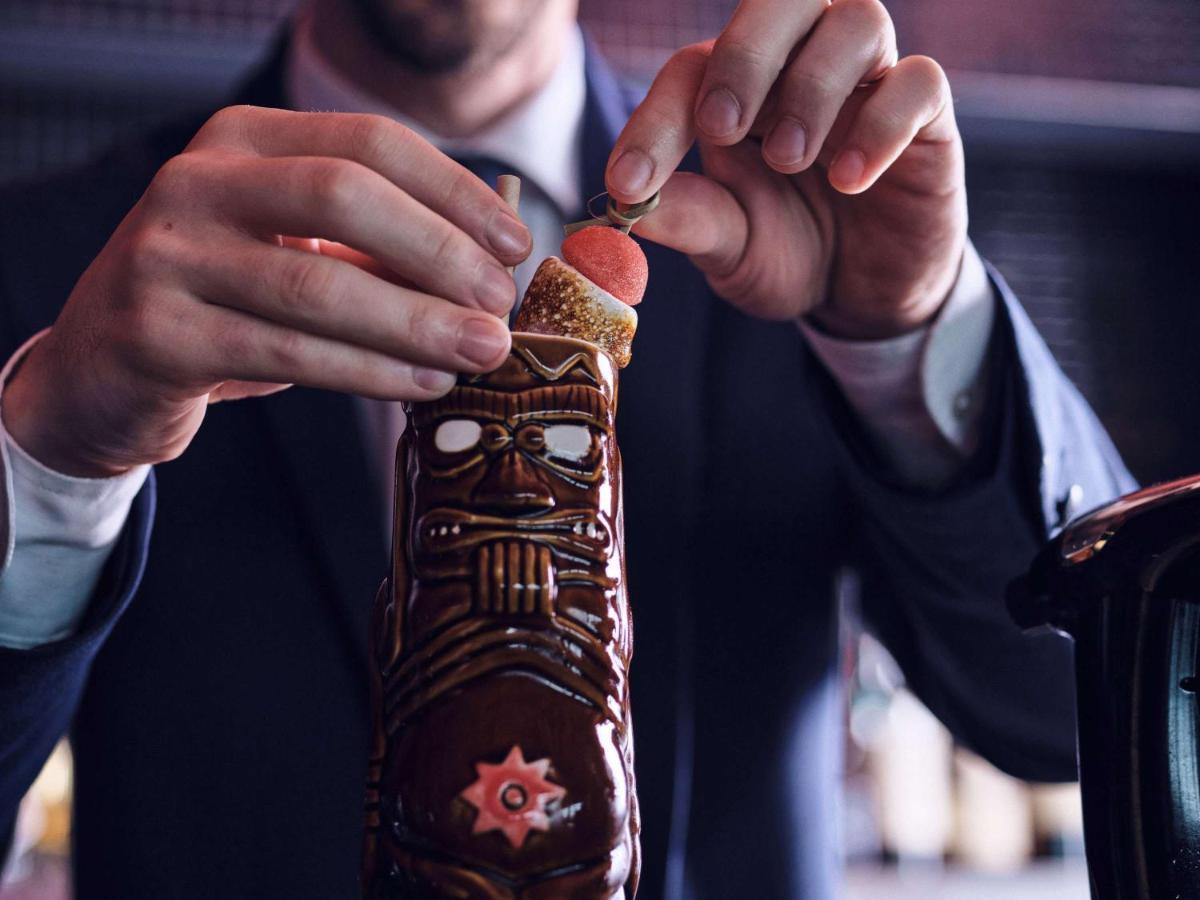 소피텔 리옹 벨쿠르 호텔 외부 사진 A bartender opening a bottle of bitters